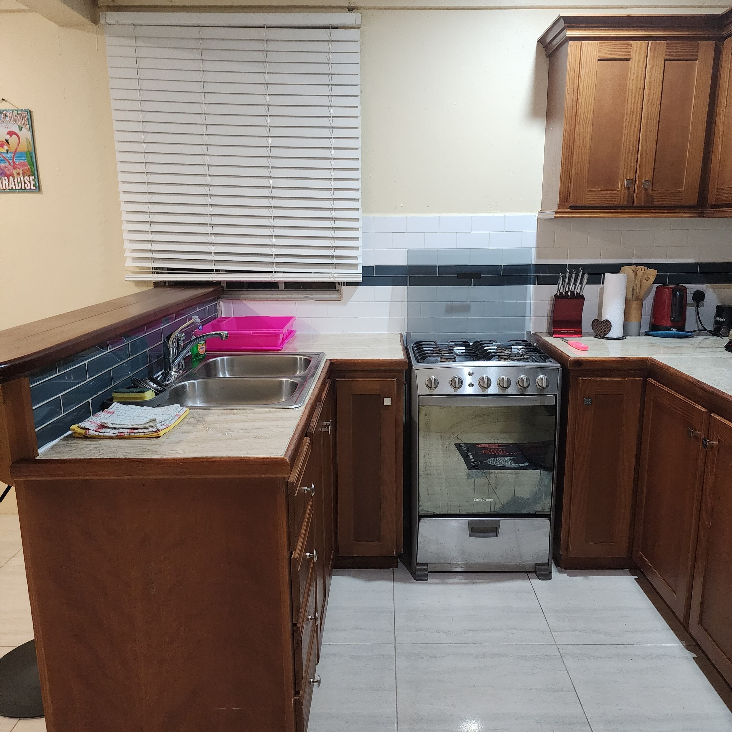Una cocina con armarios de madera, un lavamanos de acero inoxidable, una estufa a gas y un horno.