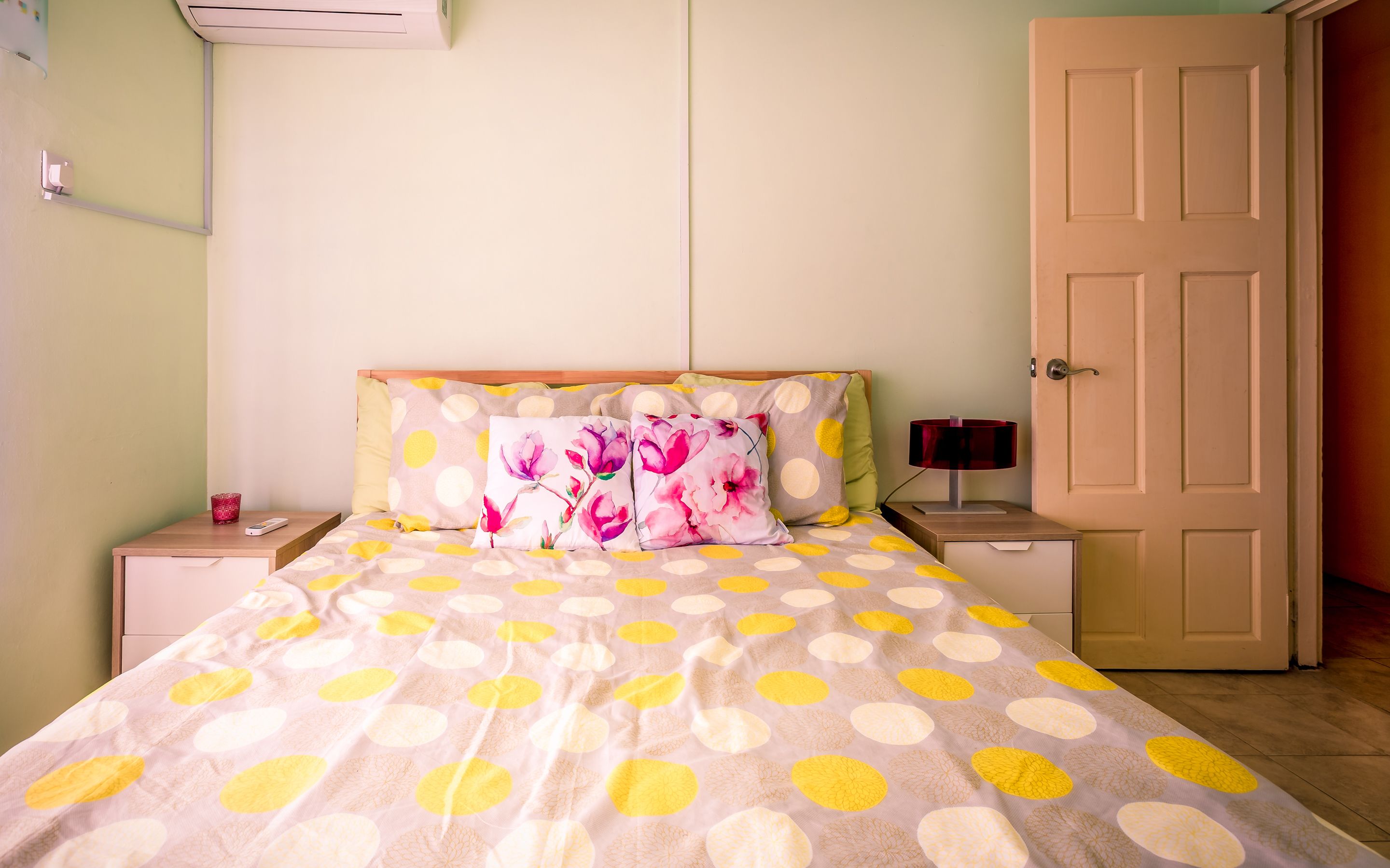 A bedroom with a bed, two nightstands, a lamp, and a door.