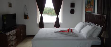 Una camera da letto con un letto, una televisione, una cassettiera e una finestra con tende.
