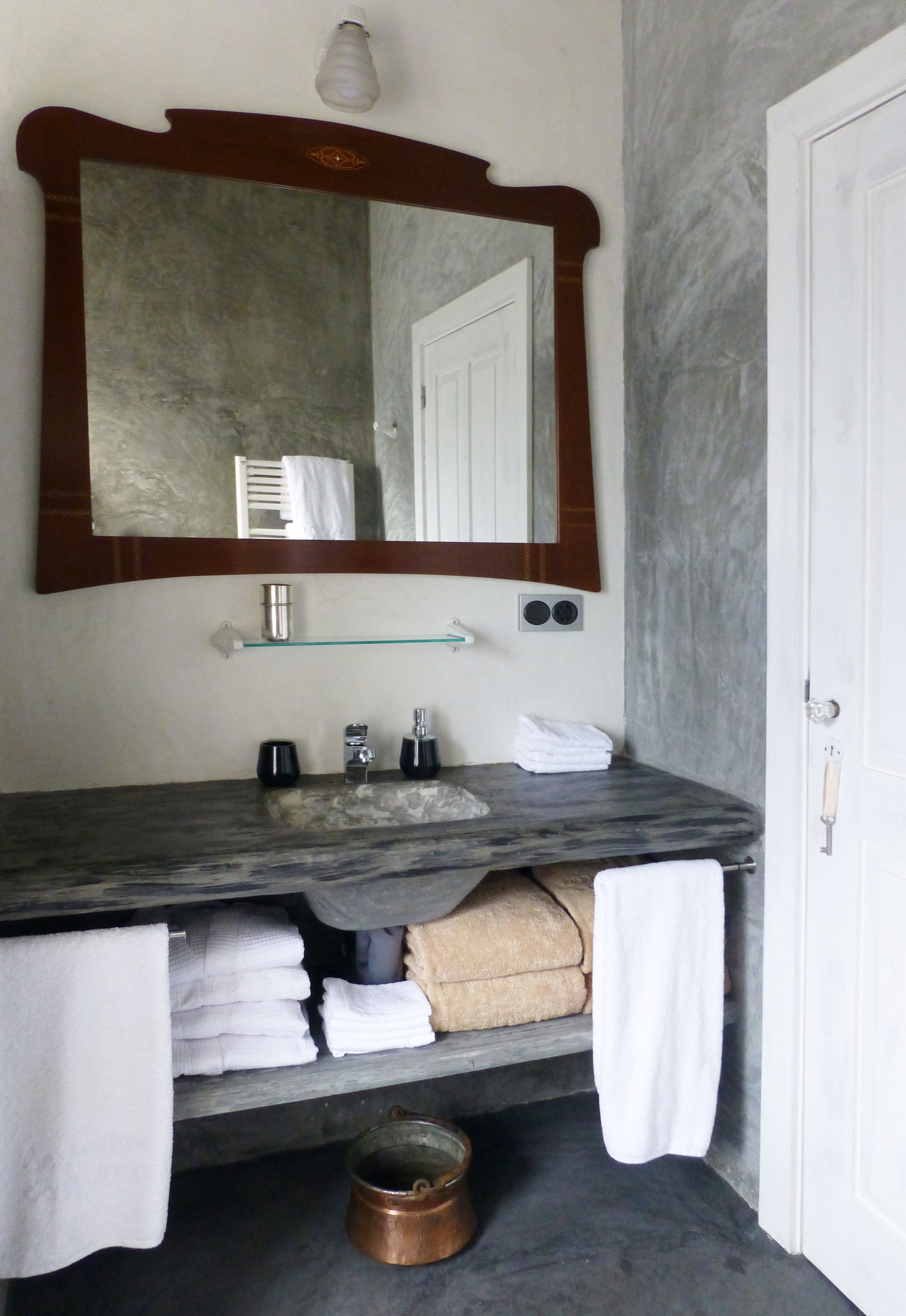 A bathroom with a marble sink, a large mirror, a towel rack, and a door.