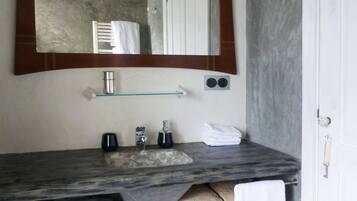 A bathroom with a marble sink, a large mirror, a towel rack, and a door.