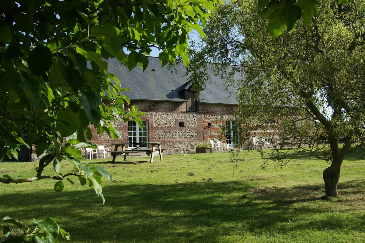 A stone building with a sloped roof, surrounded by a grassy lawn and trees.