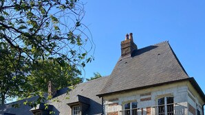 A two-story house with a stone facade, a wooden door, and a small balcony. - Gîtes Normands de charme Les Châtaigniers (Bretteville-du-Grand Caux)