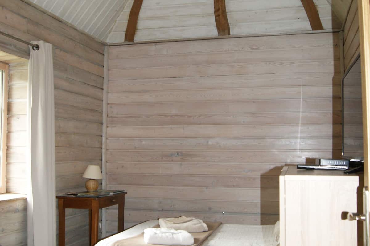 A bedroom with a bed, a nightstand, a lamp, and a wardrobe.