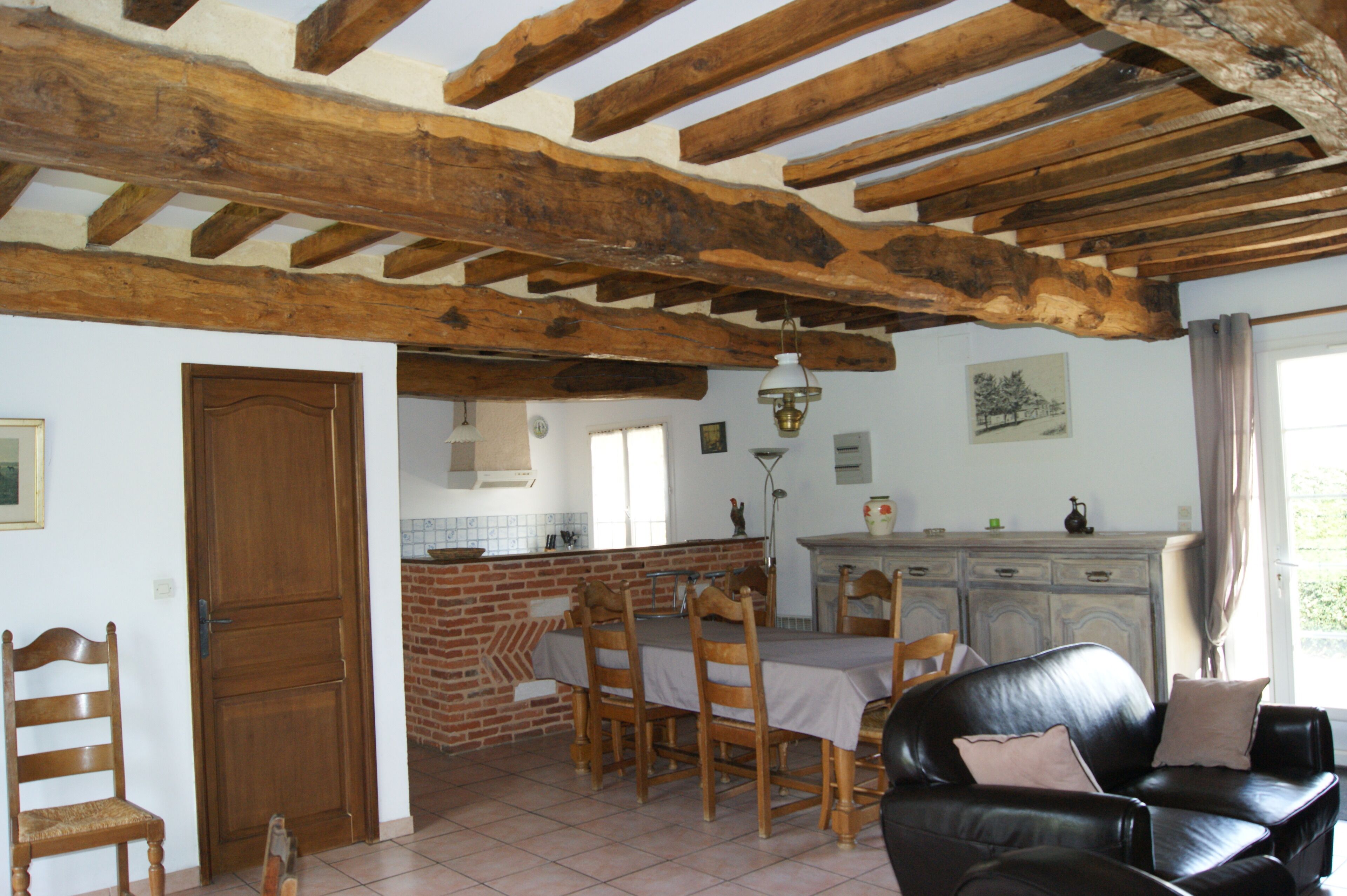 Comedor con pared de ladrillo, vigas de madera en el techo y una mesa preparada para cuatro comensales.