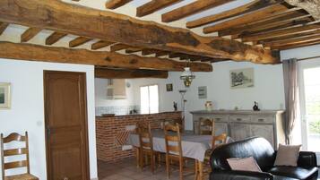 Comedor con pared de ladrillo, vigas de madera en el techo y una mesa preparada para cuatro comensales.