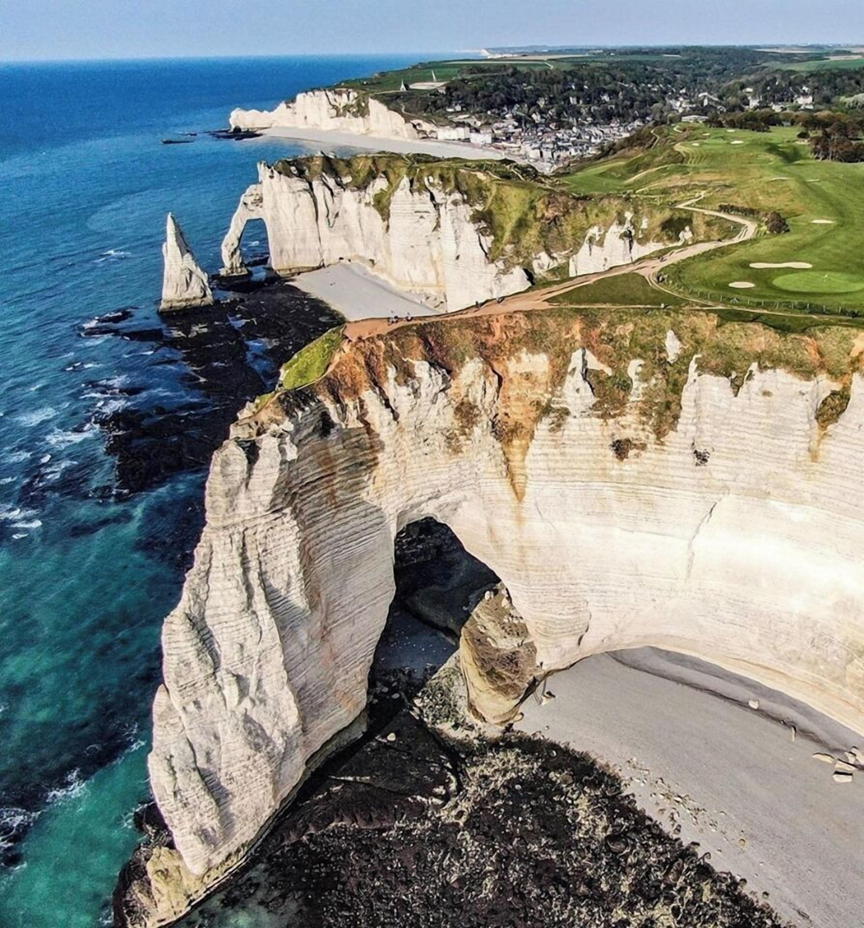 Un paisaje costero con una imponente formación rocosa blanca y un campo de golf.