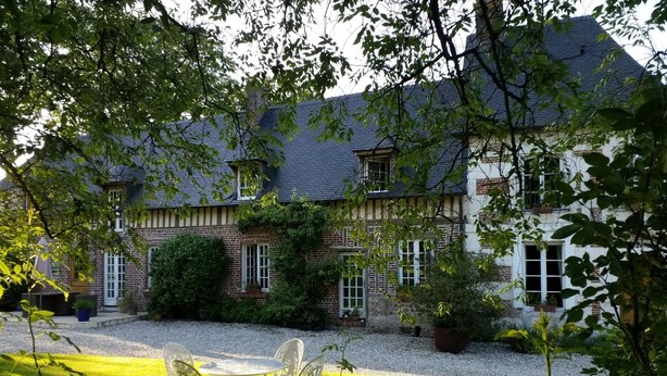 A two-story house with a brick facade, a gravel driveway, and a lawn with a table and chairs. - Gîtes Normands de charme Les Châtaigniers (Bretteville-du-Grand Caux)