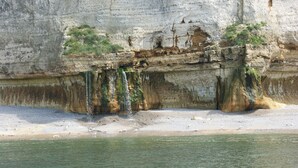 A coastal cliff with a sandy beach and a calm sea. - Gîtes Normands de charme Les Châtaigniers (Bretteville-du-Grand Caux)