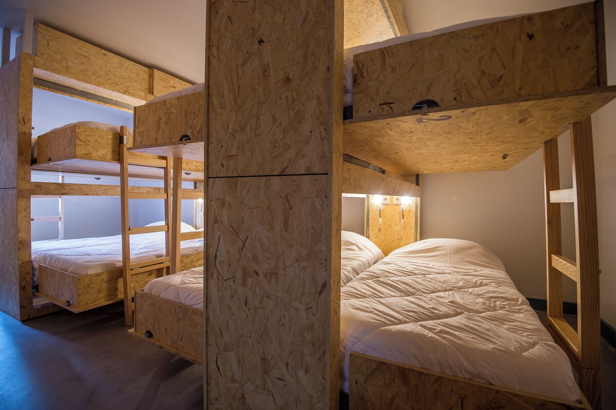 Una habitación con literas, paredes de madera y un diseño sencillo y funcional.