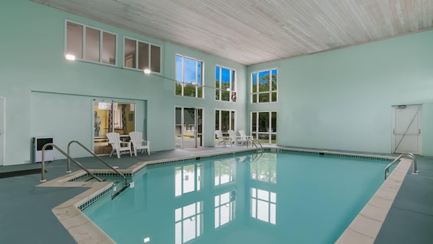 Une piscine intérieure à l’eau claire, entourée de murs bleu pâle et surmontée d’un plafond en bois.