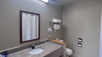 Un baño con lavamanos de granito, un espejo, toallero, inodoro y cortina de ducha.