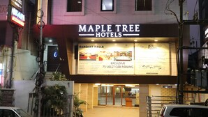 Un hôtel appelé Maple Tree Hotels, avec une enseigne indiquant la présence de salles de réception et proposant un service de voiturier pour le stationnement des véhicules, couvrant 75 % des places.