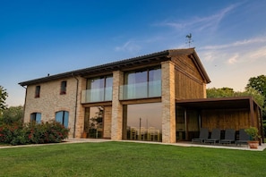 A two-story building with a stone facade, large windows, and a covered outdoor seating area.