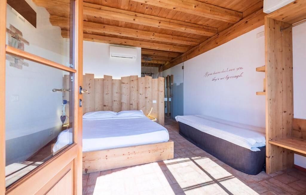 A wooden room with a bed, a bench, and a wall with a quote.