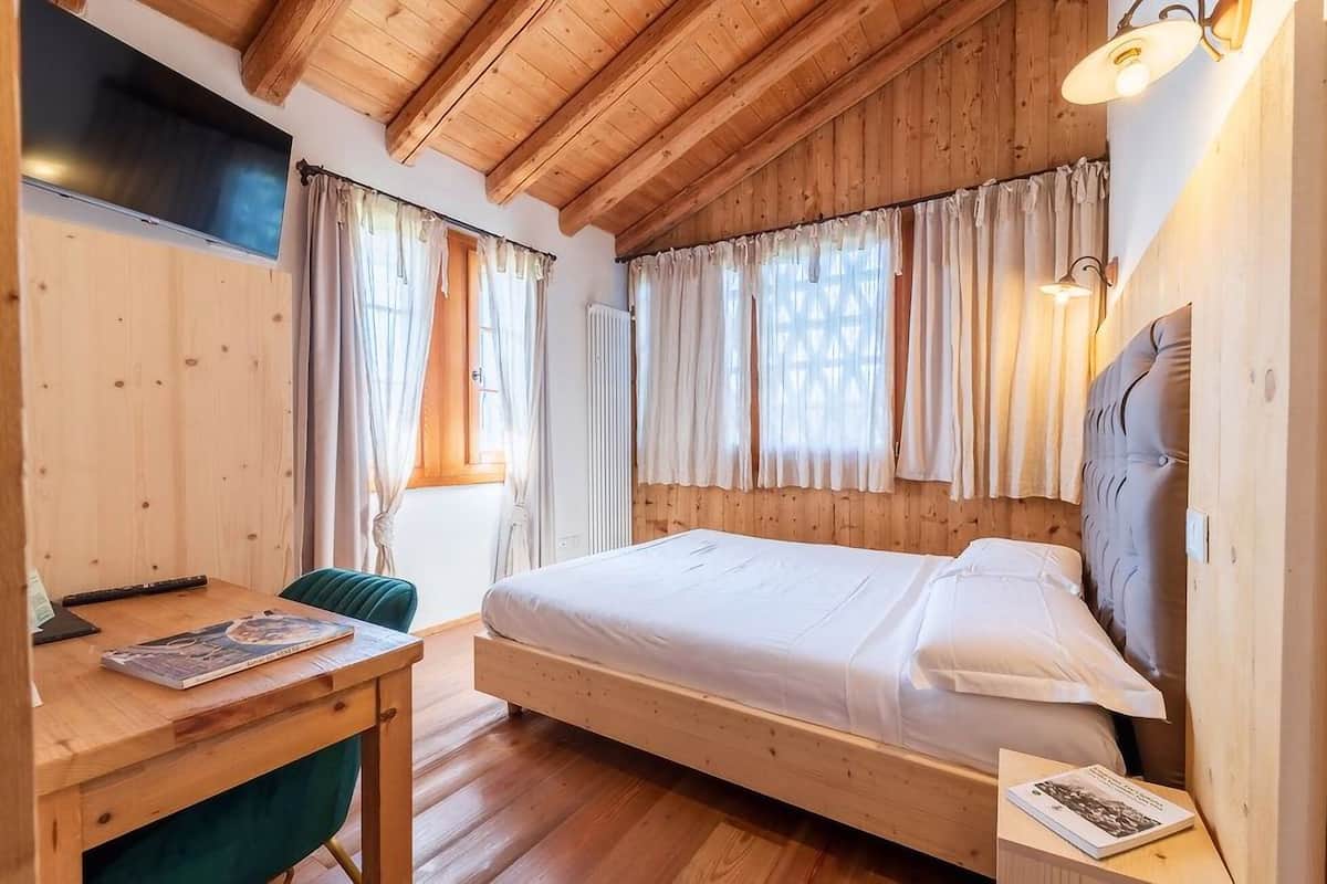 A wooden-paneled room with a bed, a desk, and a chair.