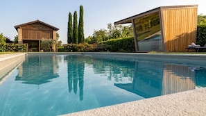 A swimming pool with a wooden building and a glass structure in the background.