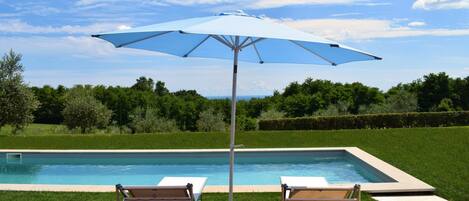Een buitenzwembad, parasols voor strand/zwembad