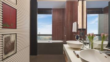 A modern bathroom with two large sinks, a bathtub, and a city view.