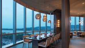 A modern dining area with a long table, chairs, and hanging pendant lights. - Grand Hyatt Changsha (Changsha)