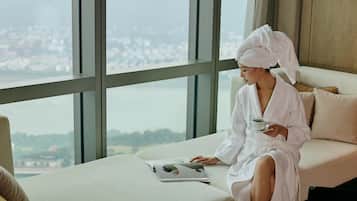 Guests can unwind in a serene space with a city view, featuring a comfortable bench and a bathtub.