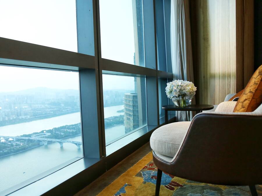 A modern room with a large window overlooking a river and cityscape.