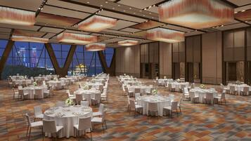 A large banquet hall with round tables set for dining, featuring a patterned carpet and modern ceiling lights.