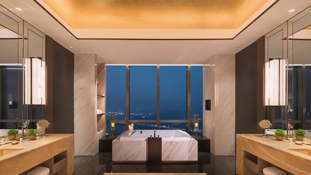 A modern bathroom with a large bathtub, two vanity mirrors, and a city view. - Grand Hyatt Changsha (Changsha)