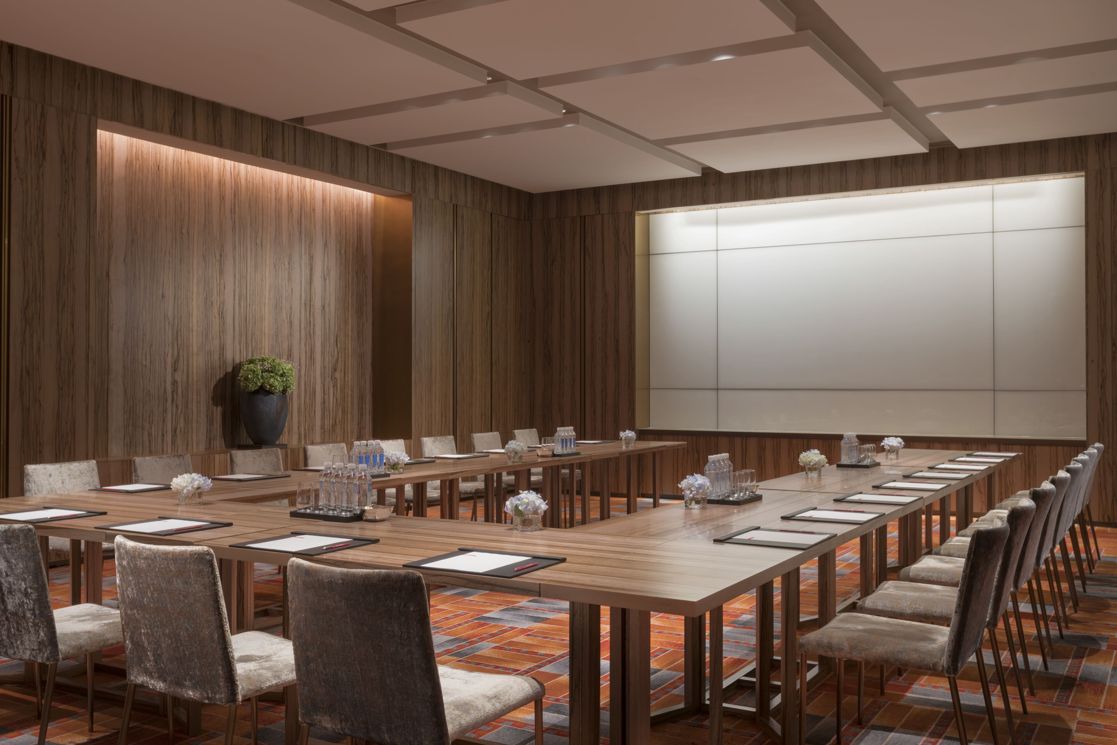 Un salón de conferencias con una larga mesa de madera, varias sillas y una pizarra grande.