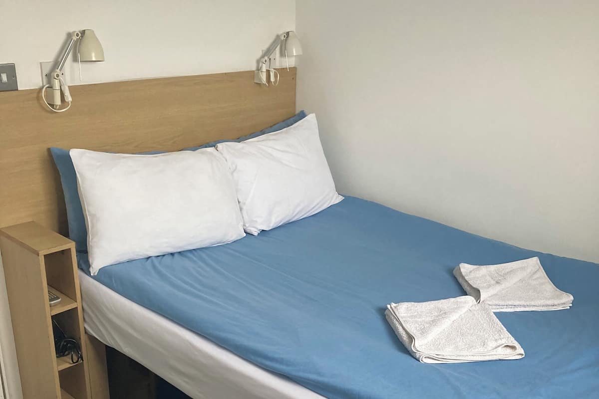 A neatly made bed with blue and white bedding, two pillows, and two folded towels.