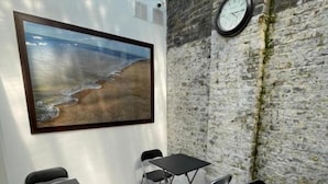 Una sala de reuniones con pared de piedra, un reloj y un cuadro enmarcado con una playa.