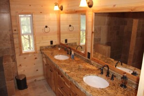 A wooden cabin bathroom with two sinks, a large mirror, and a window.