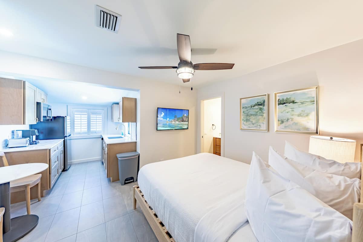 A hotel room with a bed, a desk, a chair, a television, and artwork on the walls.