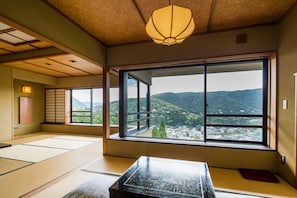 A traditional Japanese room with tatami flooring, a low table, and a large window offering a view of a mountainous landscape. - Washintei Hogetsu (Hakone)