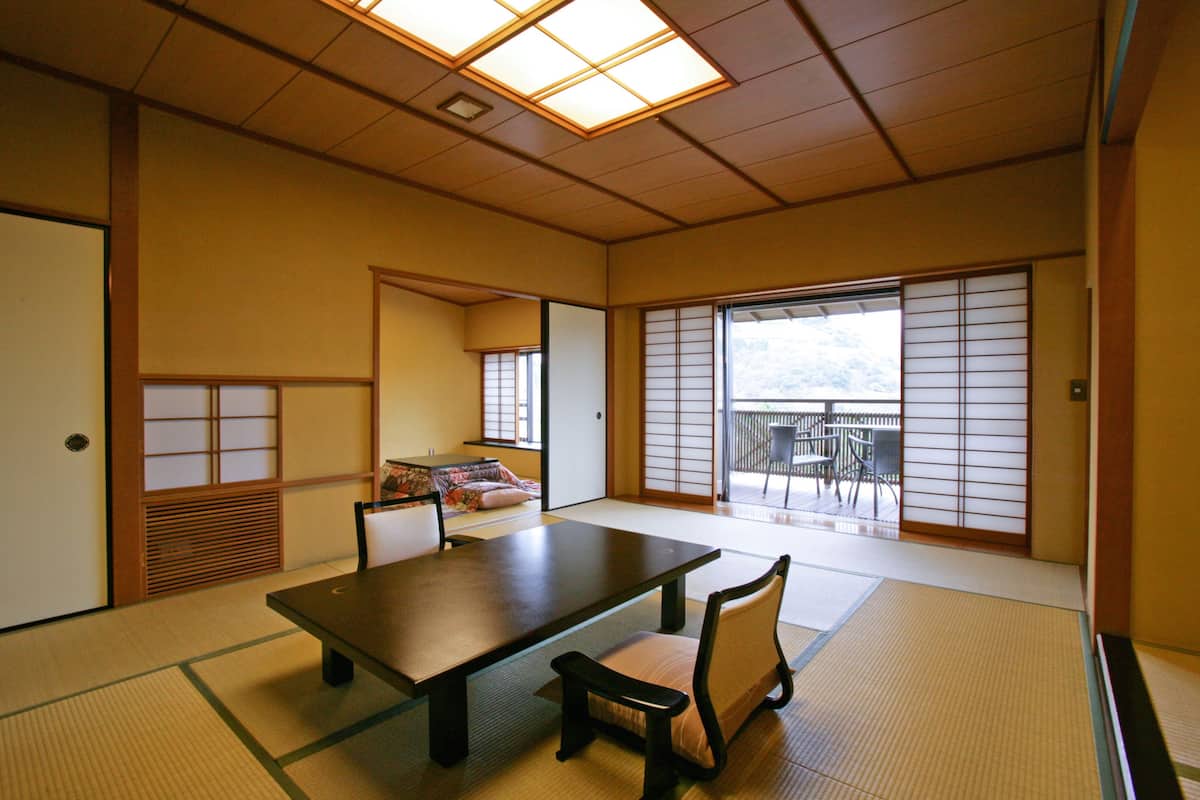 A traditional Japanese room with tatami flooring, a low table, and sliding doors.
