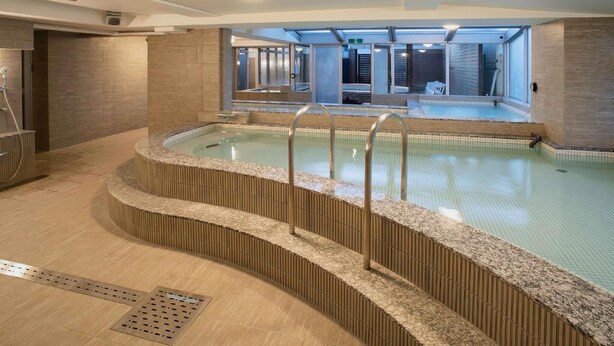A modern indoor swimming pool with a clear view of the adjacent building's interior. - Ikebukuro Royal Hotel (Tokyo)