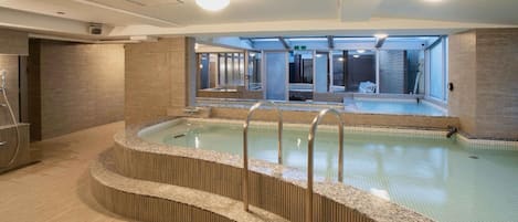 A modern indoor swimming pool with a clear view of the adjacent building's interior.