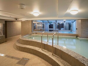 Ein moderner, überdachter Pool mit freiem Blick auf das Innere des angrenzenden Gebäudes.