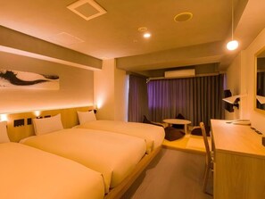 Ein Hotelzimmer mit zwei Betten, einem Schreibtisch und einem kleinen Tisch.