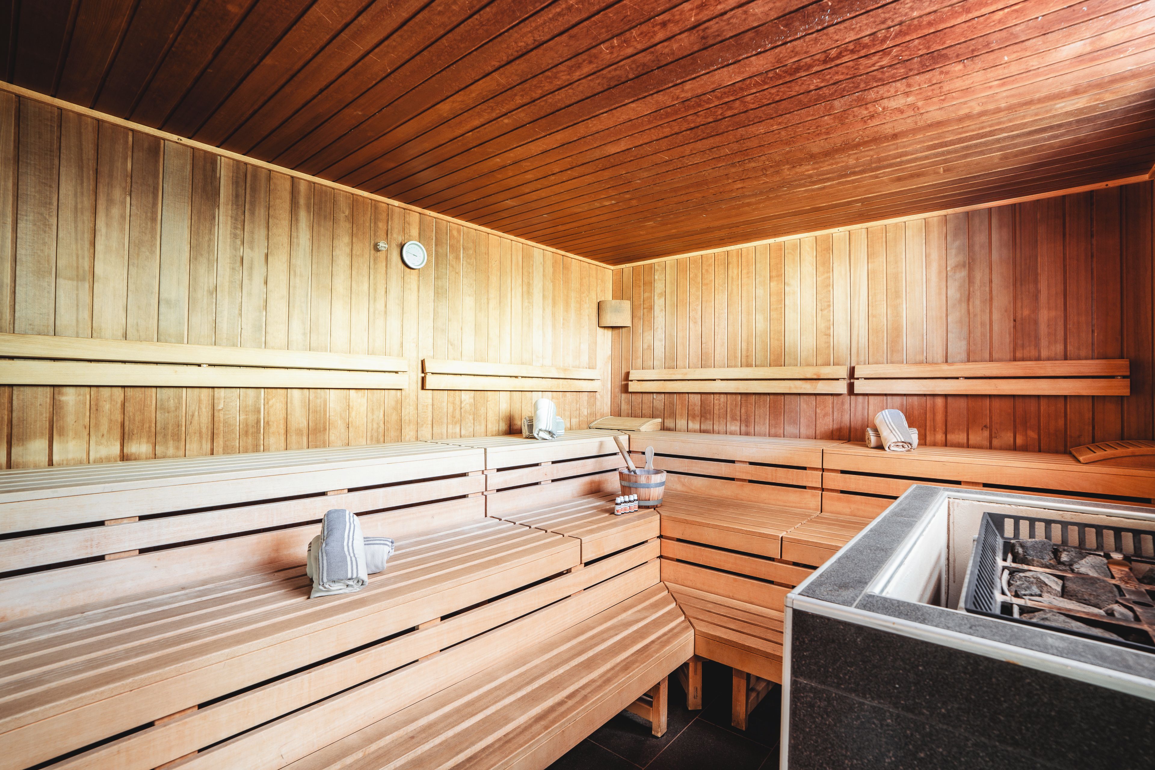 Una sauna con bancos de madera y un elemento calefactor de piedra.