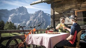 Una cabaña de madera con una mesa dispuesta para dos, una bicicleta y vistas a la montaña.