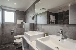 A modern bathroom with two sinks, a toilet, and a large mirror. - Monte Croce Hotel Kreuzberg (Sesto)