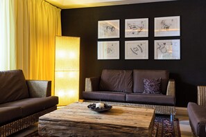 A living room with a dark wall, a sofa, a coffee table, and a lamp. - Monte Croce Hotel Kreuzberg (Sesto)