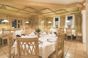 A dining area with wooden paneling, white tablecloths, and neatly set tables with chairs. - Monte Croce Hotel Kreuzberg (Sesto)