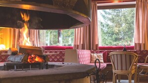 Una camera accogliente con camino, un divano rosso con motivi decorativi e una finestra con tende.