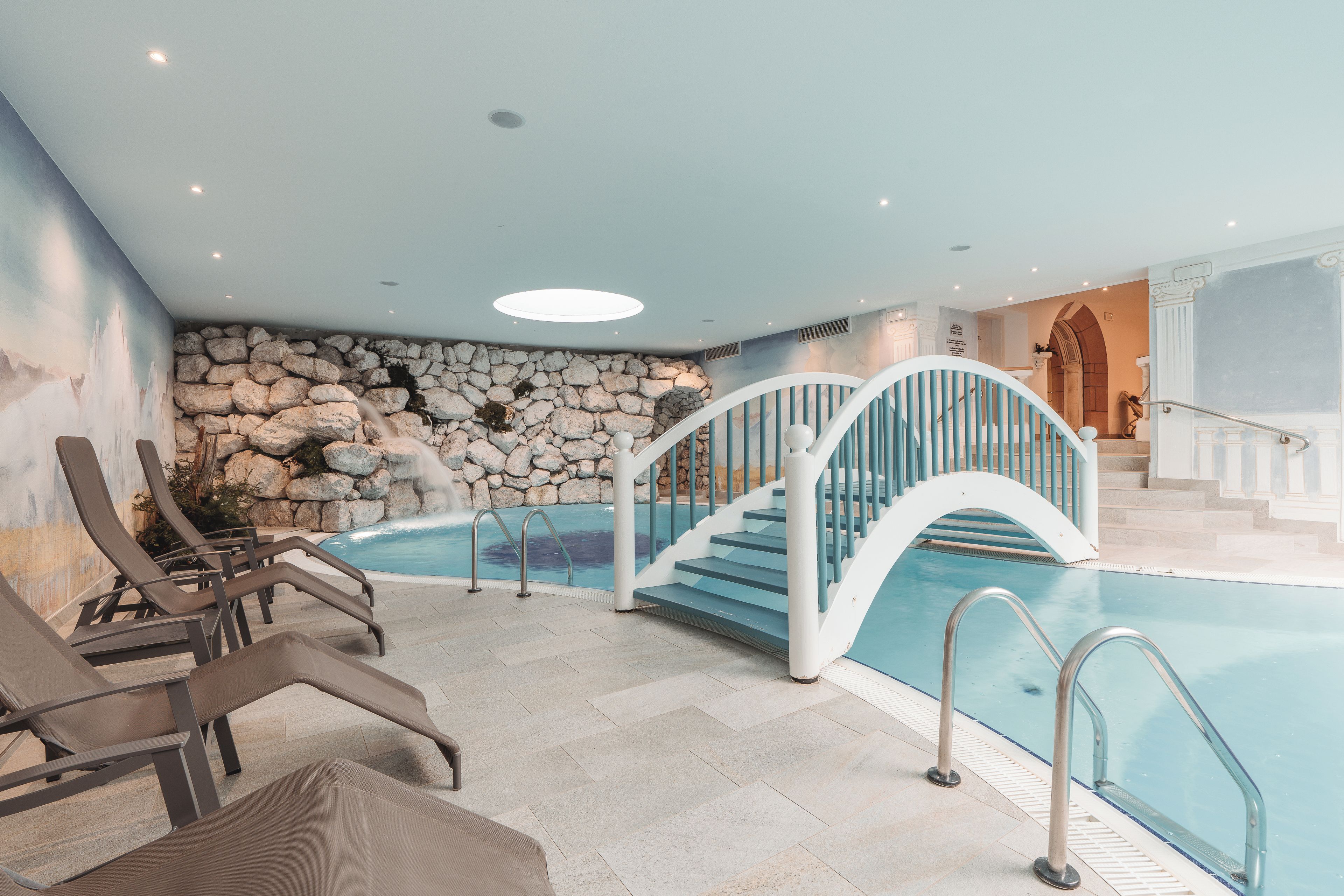 Un espace piscine agrémenté d’un mur en pierre, d’un escalier et de chaises longues.