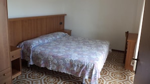 Una cama individual con una colcha estampada en una habitación con suelo estampado y muebles de madera.