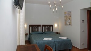 A bedroom with two beds, a wooden table, and a chair. - DolceVita Sorrento Guest House (Sorrento)