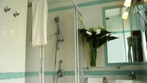 A bathroom with a shower, a sink, a mirror, and a vase with flowers. - DolceVita Sorrento Guest House (Sorrento)