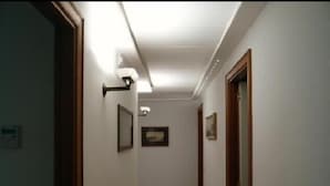 A narrow hallway with white walls, wooden doors, and a patterned floor. - DolceVita Sorrento Guest House (Sorrento)
